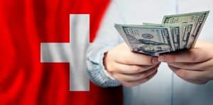 Une personne compte des billets de dollars américains devant un drapeau suisse, envisageant peut-être des aides financières ou des subventions pour des pompes à chaleur.