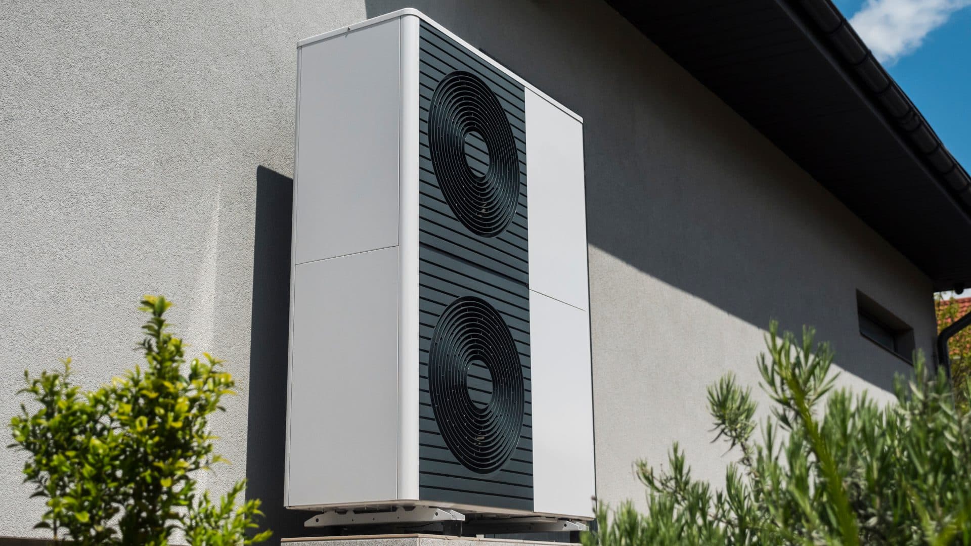 Pompe à chaleur moderne avec deux évents circulaires installée sur le mur extérieur d'un bâtiment, entourée de choisir une pompe à chaleur