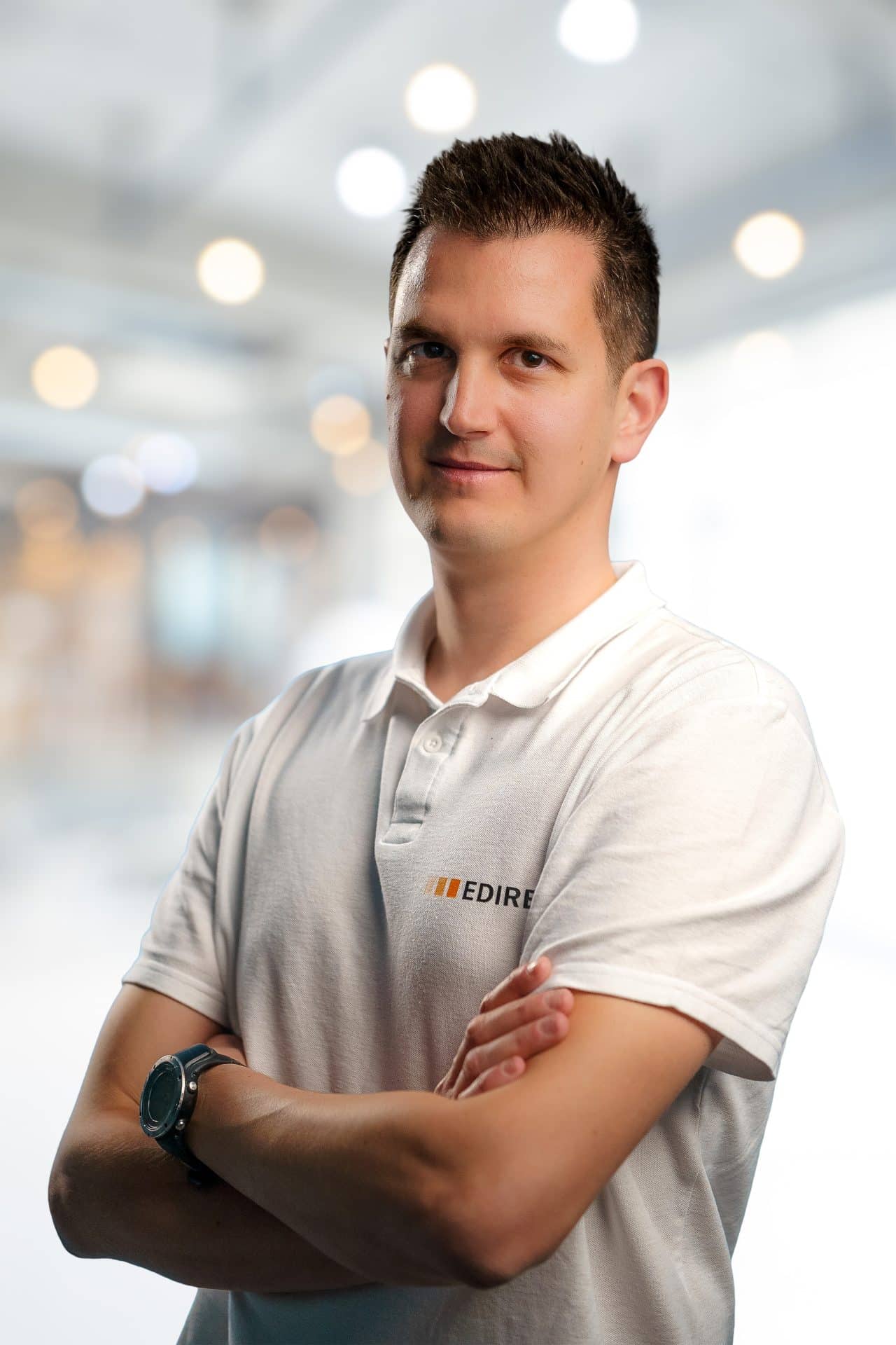 http://Un%20homme%20vêtu%20d'un%20polo%20blanc%20portant%20le%20logo%20EDIRE%20se%20tient%20debout,%20les%20bras%20croisés,%20regardant%20la%20caméra%20dans%20un%20décor%20intérieur%20éclairé%20et%20flou,%20incarnant%20la%20réussite%20de%20ses%20projets.